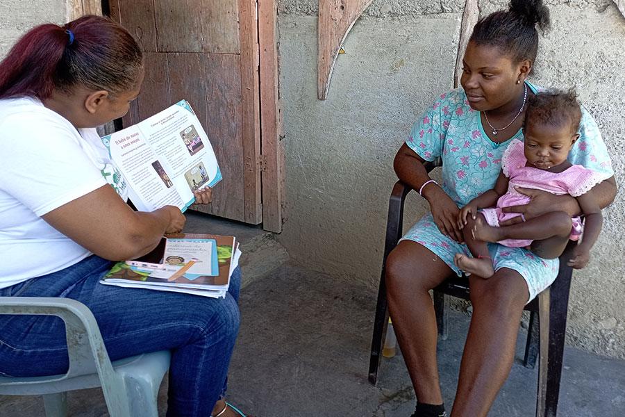 Mujer entrevistando a mujer con bebé en brazos