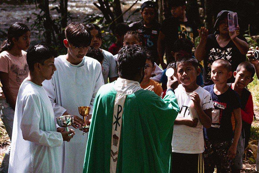 Sacerdote ofreciendo eucaristía a grupo de niños